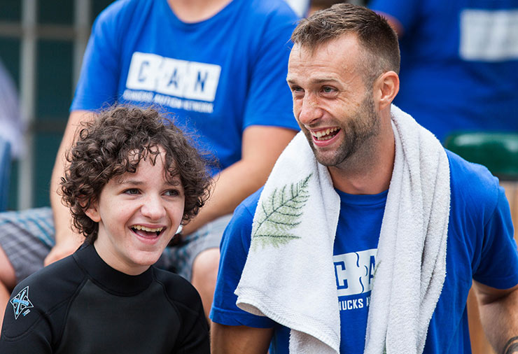 A child with autism and his support worker laughing together in our Overnight Camp program.