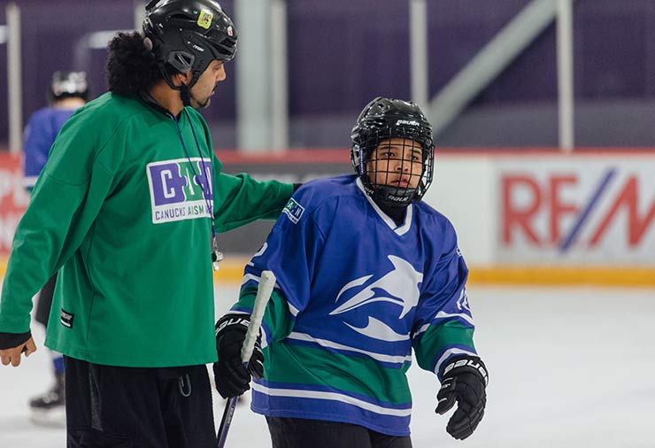 A coach and a child with autism on the ice together in our hockey program