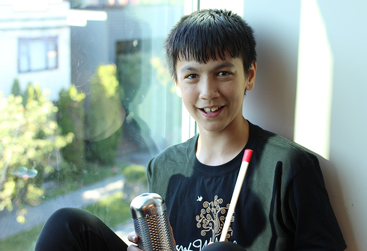 A teenager with autism poses with his instruments in our Sarah McLachlan School of Music program.