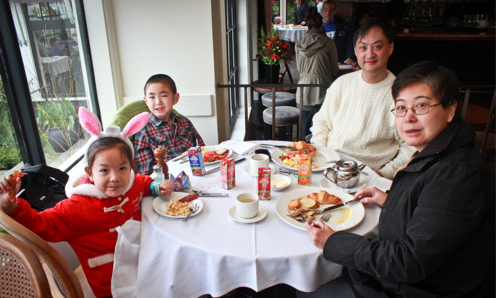 A family poses for a photo while seated around a restaurant dinner table.