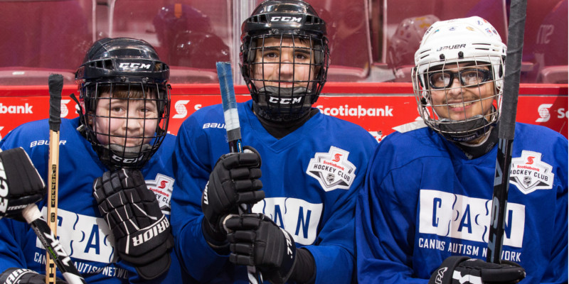 Three young hockey players sitting on the bench.