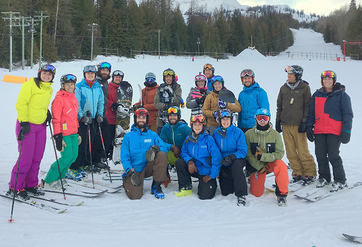 A group of adults wearing ski gear posed on a snowy mountain.