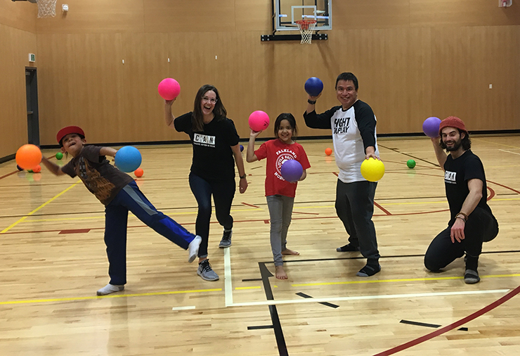 A group of children and staff ready to play dodgeball in a gymnasium.